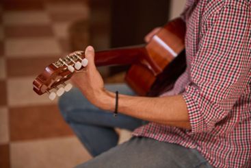 Person playing an acoustic guitar while seated indoors...