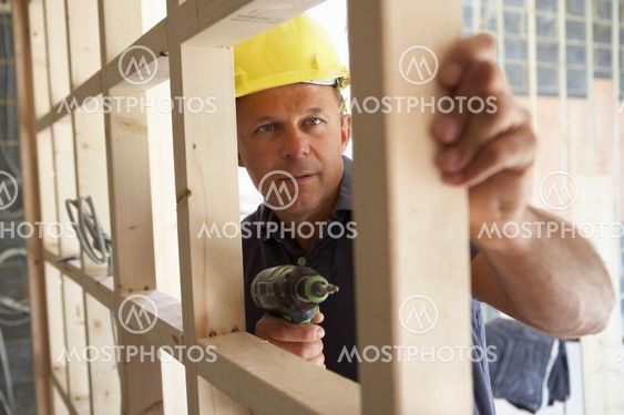 Construction Worker Building Timber Frame In New Home