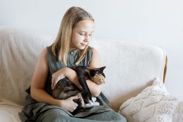 Happy young girl and cat pet together at home....