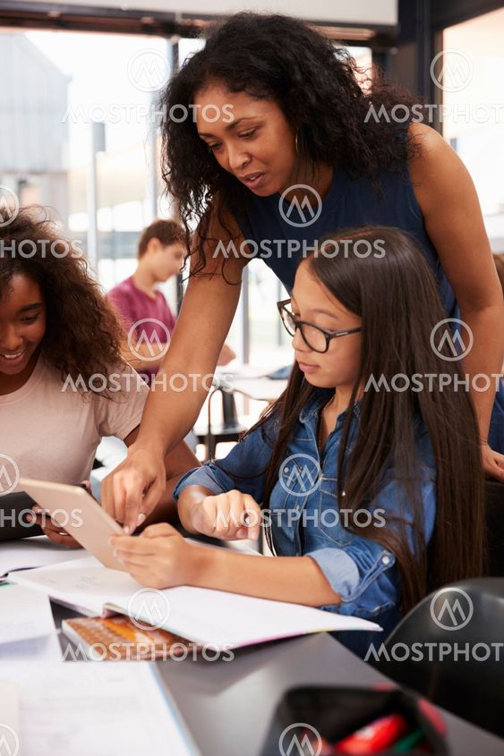 Teacher helps high school student with technology, vertical