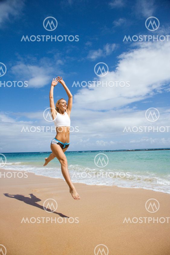 Woman jumping on beach.