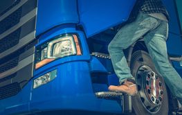 Worker Climbs Into Blue Semi Truck During Daylight at a...
