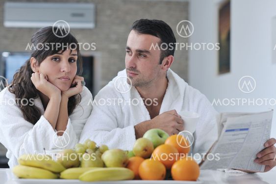 Happy couple reading the newspaper in the kitchen at breakfast