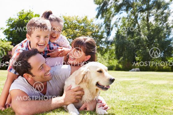 Family Relaxing In Garden With Pet Dog