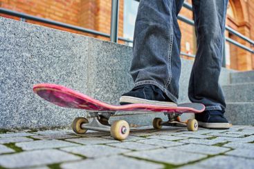 Skateboarder riding on pink skateboard at city street
