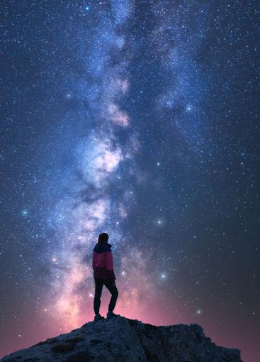 Milky Way and woman on mountain peak at starry night....