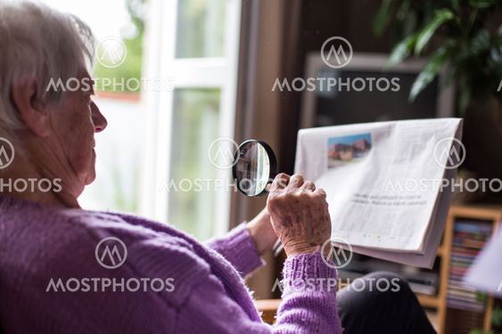 Senior woman reading morning newspaper, sitting in her...