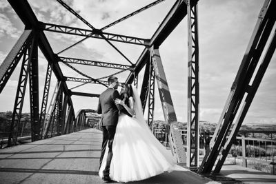 Wedding couple in love stay at red railway bridge.