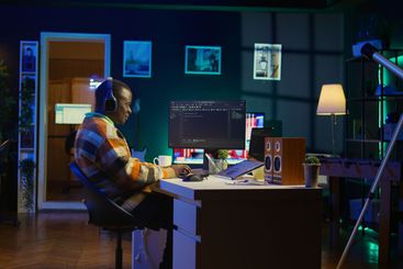 Black programmer remotely working in home office writing...