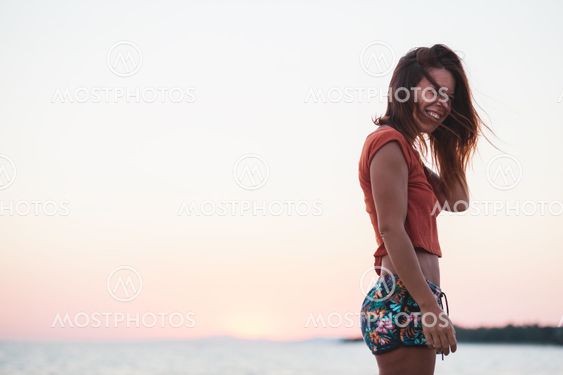 Young woman enjoying sunset by the sea
