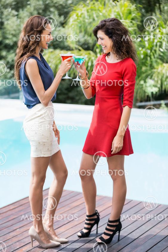 Cheerful female friends toasting cocktails