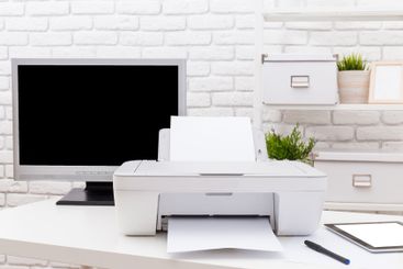 Home office setup with a printer, computer monitor, and...