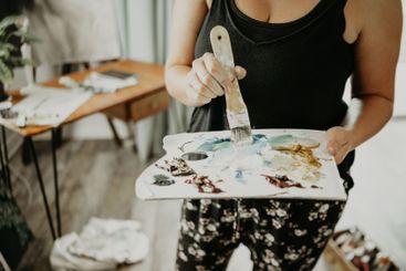 Paint, palette and hands of woman in art studio at home...