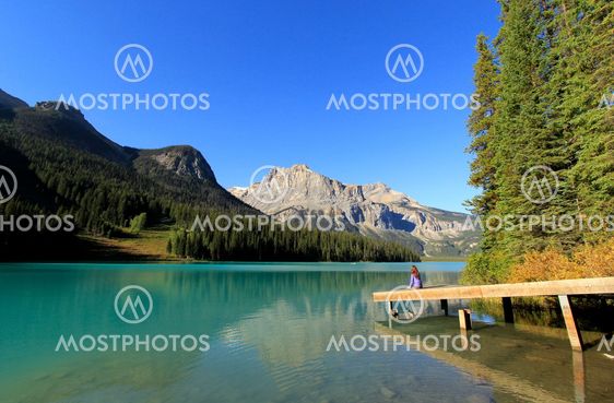 Young woman sitting on a pier at Emerald Lake, Yoho...