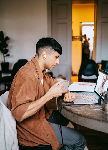 Side view of male freelancer having coffee while doing...