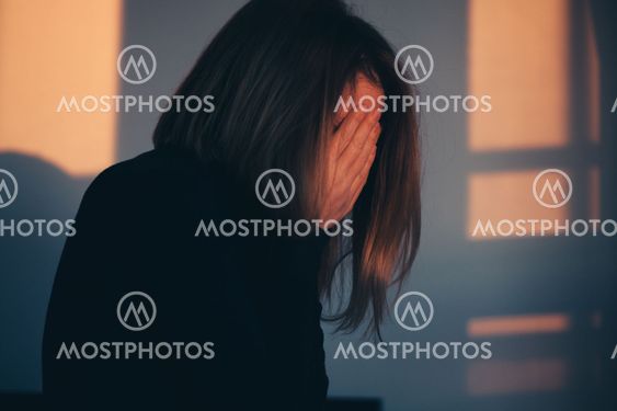 A woman sitting alone and depressed in window light