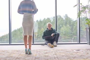 A blonde man sitting casually on the floor of a modern...