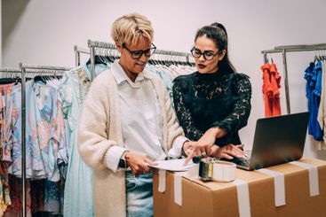 Female owner talking with colleague while working on...