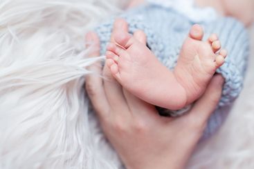 Newborn baby feet in mother hands. Parental love and care