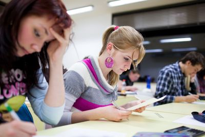 pretty female college student sitting in a classroom full...