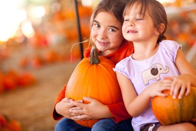Cute Little Girls Holding Their Pumpkins At A Pumpkin Patch