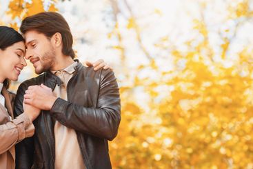 Emotional lovers cuddling during date at autumn forest