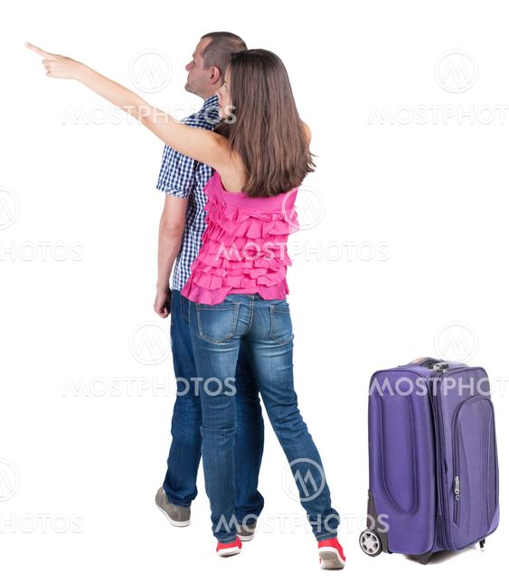 young couple traveling with suitcas and pointing at wal...