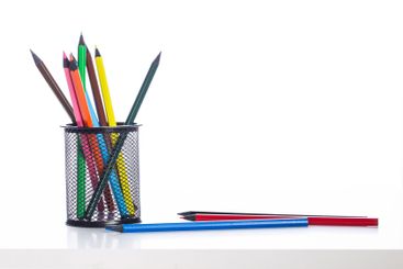 Colorful pencils arranged in a black mesh holder on a...