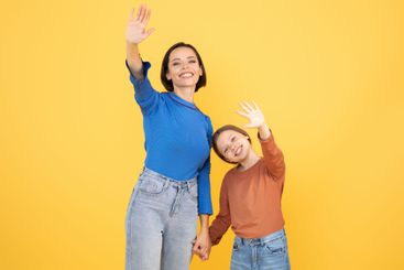 Mother and daughter share a joyful moment waving...