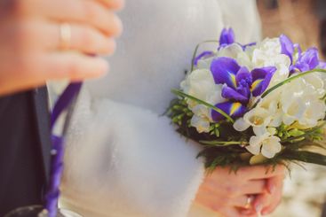 Vibrant bouquet of purple and white flowers held during...