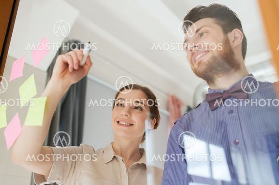happy creative team writing on blank office glass