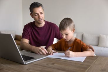 Dad helps with assignment to his little school age son