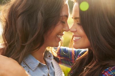 Lesbian couple embrace touching noses, eyes closed, close...