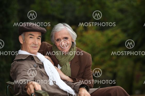 Elegant elderly couple sitting on a park bench