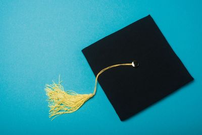 Black graduation cap with tassel brush on blue background