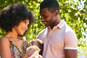 Loving Parents Cuddling Sleeping Baby Daughter Outdoors...