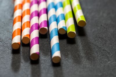 Multicoloured drink straws on dark stone background....