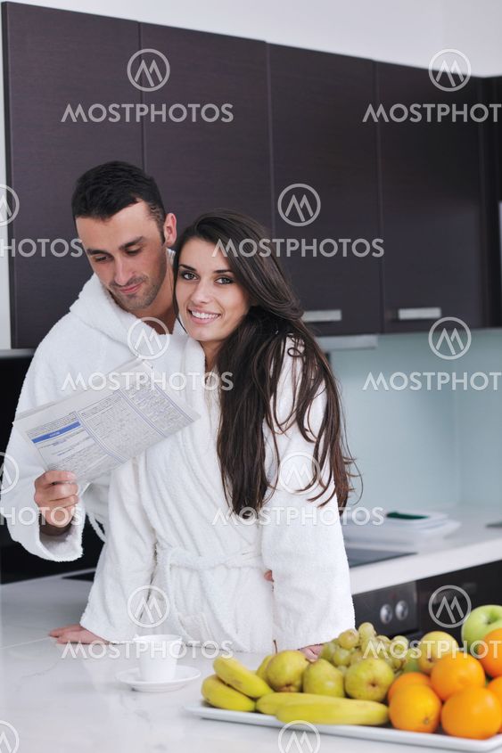 Happy couple reading the newspaper in the kitchen at breakfast