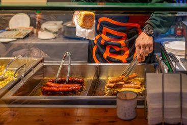 Grilled sausages being prepared at a food stall by male...