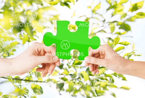 hands with green puzzle over natural background
