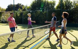 Happy diverse group of friends playing tennis, shaking hands