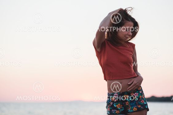 Young woman enjoying sunset by the sea