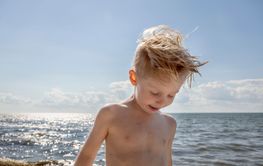 Shirtless boy under clouds at beach