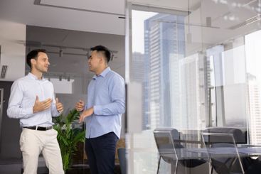 Two positive male business colleagues discussing...