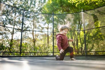 Little boy jumping on a trampoline in a backyard on warm...