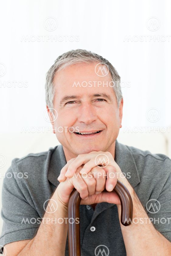 Mature man with his walking stick on his bed