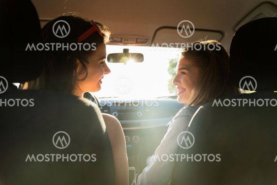 happy teenage girls or women driving in car