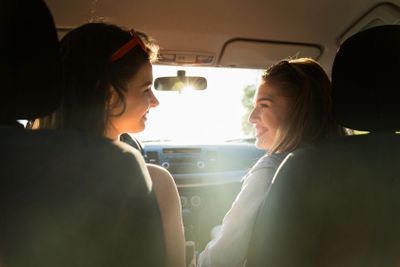happy teenage girls or women driving in car