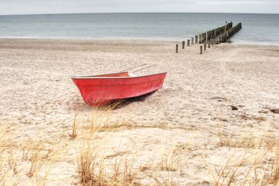 Fishermens boat at seacoast, on sand at sunset with...