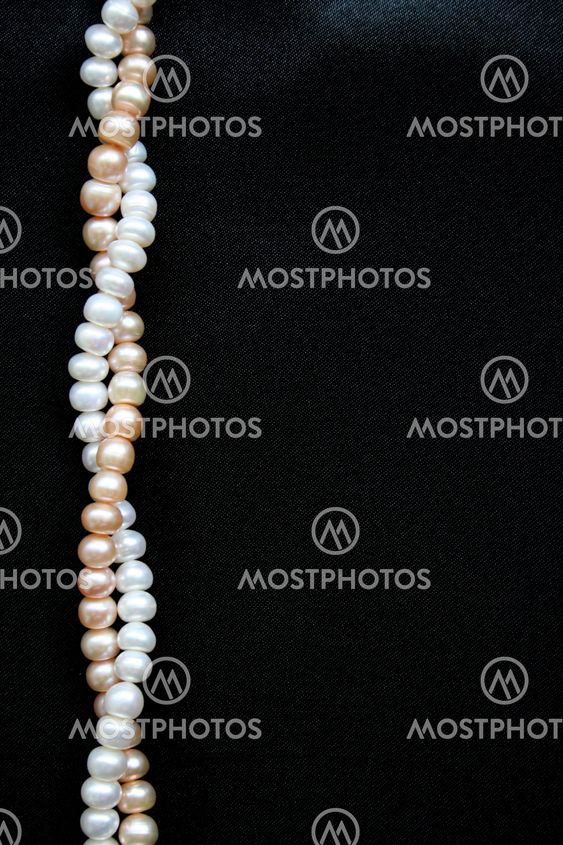 White and pink pearls on the black silk background